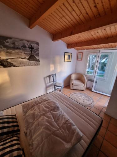 une chambre avec un grand lit et une chaise dans l'établissement Instants de détente et de partage aux sables d'or, à La Guérinière