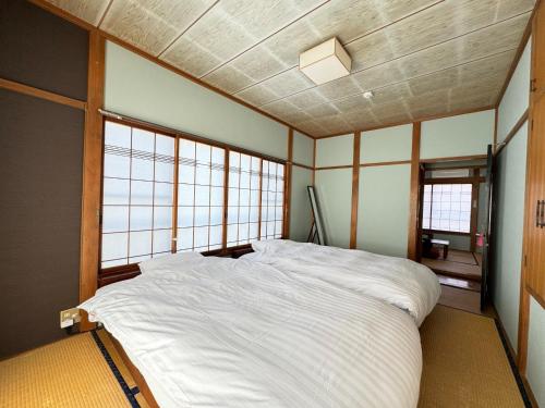 Calmbase Nishi Izu - Vacation STAY 30929v في Toda: سرير أبيض كبير في غرفة بها نوافذ
