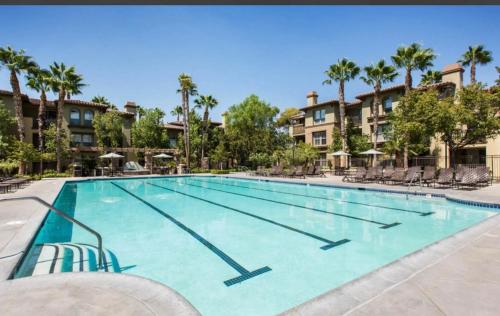 a large swimming pool with chairs and palm trees at The Plaisir - Pool & Spa in Santa Clarita