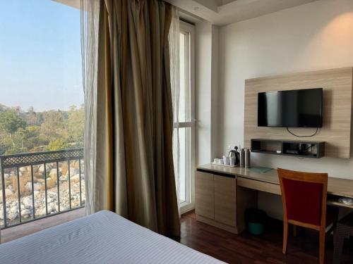 een hotelkamer met een bureau en een groot raam bij Hotel River Retreat in Kangra