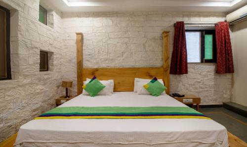 a bedroom with a large white bed with green pillows at Treebo Megh Niwas, 2 Km From Umaid Bhawan Palace in Jodhpur