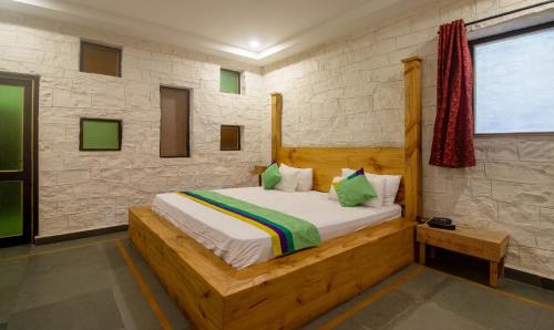 a bedroom with a wooden bed with green pillows at Treebo Megh Niwas, 2 Km From Umaid Bhawan Palace in Jodhpur