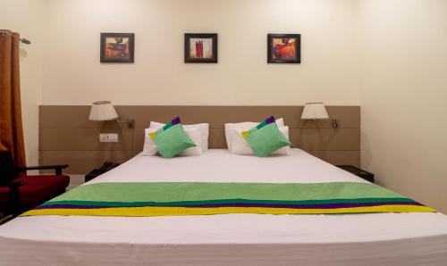 a bedroom with a large white bed with colorful pillows at Treebo Megh Niwas, 2 Km From Umaid Bhawan Palace in Jodhpur