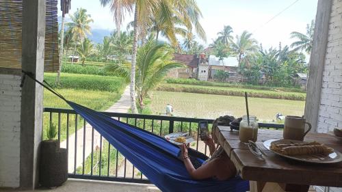 a woman laying in a hammock on a porch at MyHome - Lombok in Tetebatu
