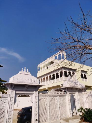 een wit gebouw met een hek ervoor bij Marcol a countryside villa in Udaipur