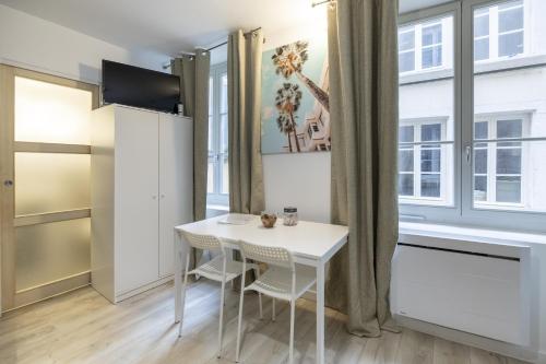 - une petite table et des chaises blanches dans une chambre avec fenêtre dans l'établissement Le petit MIAMI, à Thionville