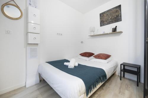 a white bedroom with a bed and a mirror at Le petit MIAMI in Thionville