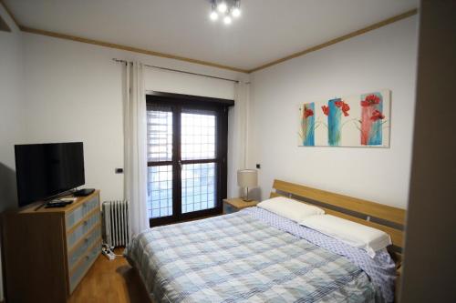 1 dormitorio con 1 cama, TV y ventana en Home Sorbara "Luxury Home", en Roma