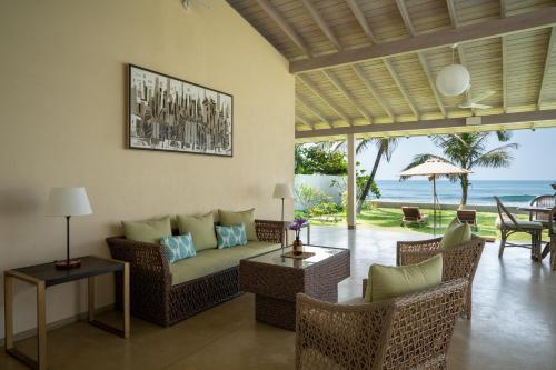 a living room with a couch and chairs and the ocean at Nil Ralla in Talpe