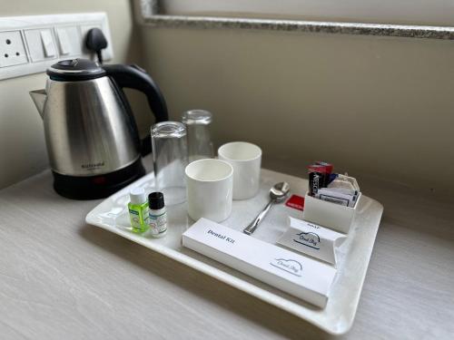 a tray with a coffee pot and cups on a counter at Cloud Stay in Guwahati