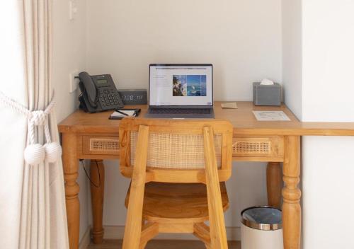 a wooden desk with a laptop and a phone at Stone Hotels Dhiffushi in Dhiffushi