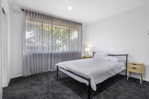 een witte slaapkamer met een bed en een groot raam bij Scenic Stay I Short or Long Term in Geelong