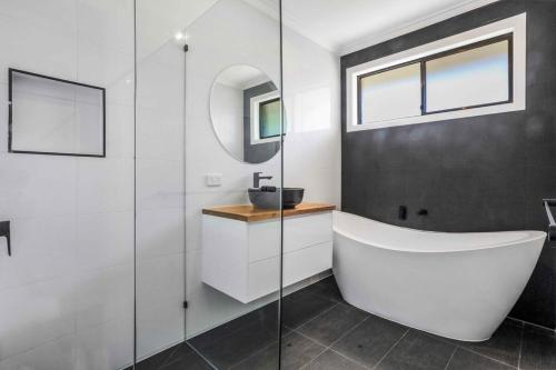 a bathroom with a tub and a sink and a mirror at Scenic Stay I Short or Long Term in Geelong