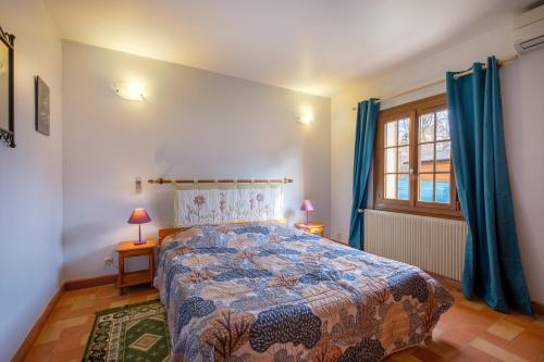 a bedroom with a bed and a window with blue curtains at Villa Madeleine in Saint-Cézaire-sur-Siagne