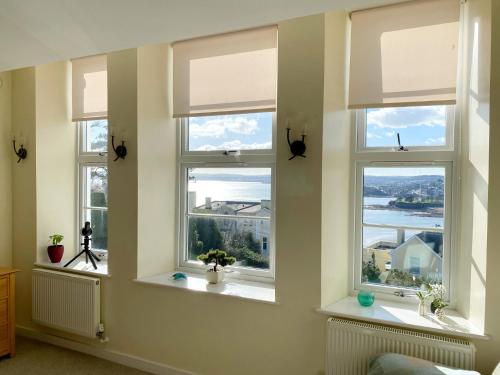 a room with three windows with views of the water at Sea View Apartment, 7 Ellington Court in Torquay