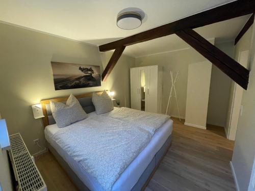 een slaapkamer met een bed met witte lakens en kussens bij Ferienwohnung Kohlbornsteinblick am Malerweg in Krippen