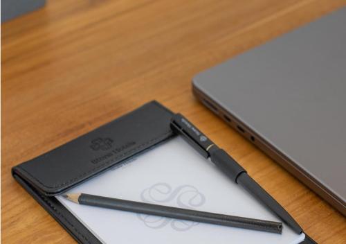 a pen and paper on a table next to a laptop at Stone Hotels Dhiffushi in Dhiffushi