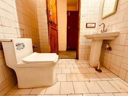 a bathroom with a toilet and a sink at Hotel Kanchan Classic Manali in Manāli