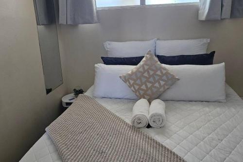 a bed with white pillows and towels on it at Sea view tranquility Durban in Durban