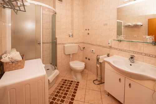 uma casa de banho com um WC, um lavatório e um chuveiro em Apartmani Trogir em Trogir