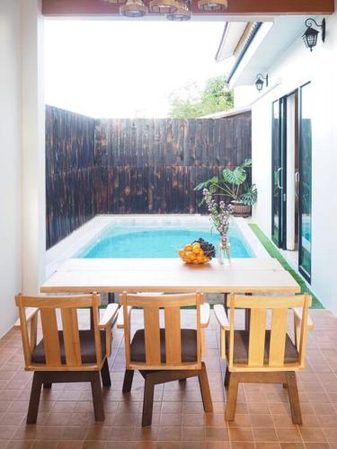 a table and chairs next to a swimming pool at Yada house onsen pool villa in Ban Nong Saeng