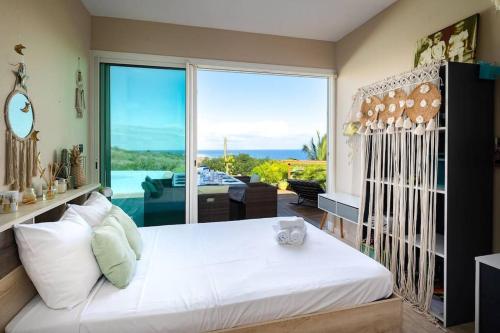 Cama blanca grande en habitación con ventana grande en Maena - Magnifique Villa de 8 personnes avec piscine et vue mer proche du lagon de Saint-Leu en Saint-Leu