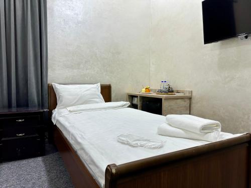 a bedroom with a bed with white sheets and towels at Rahat inn Hotel in Tashkent