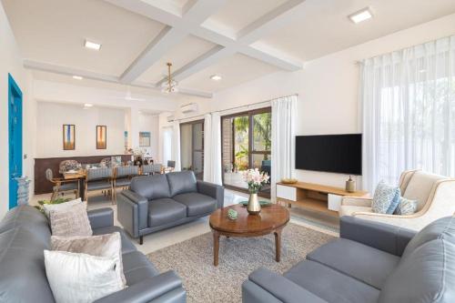 ein Wohnzimmer mit blauen Sofas und einem TV in der Unterkunft Melhor Stays Villa - Mayberry 1BHK in Arpora