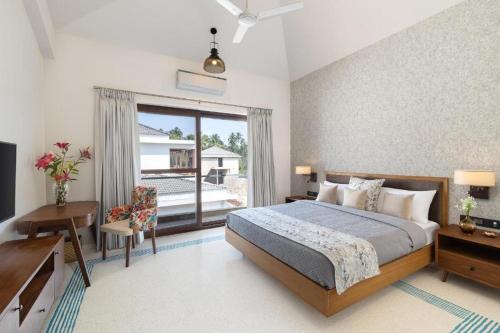 Schlafzimmer mit einem Bett, einem Schreibtisch und einem Fenster in der Unterkunft Melhor Stays Villa - Mayberry 1BHK in Arpora