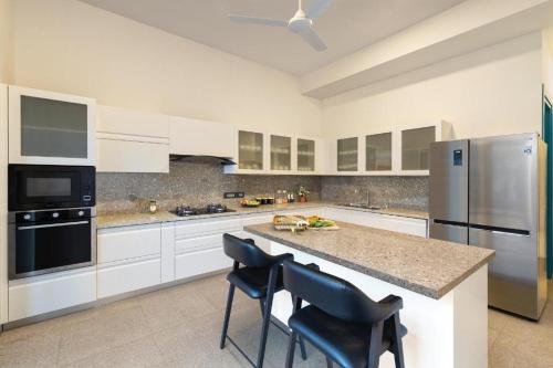 eine große Küche mit weißen Schränken und einer großen Insel in der Unterkunft Melhor Stays Villa - Mayberry 1BHK in Arpora