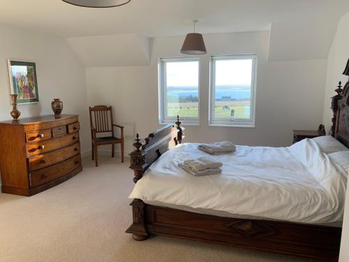 a bedroom with a bed and a dresser and two windows at Stroma, Dunnet, spacious holiday house with sauna. in Brough