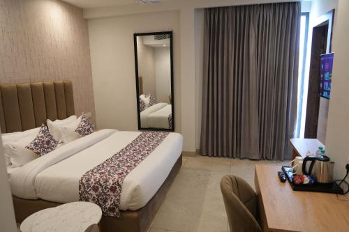 a hotel room with a large bed and a mirror at ACR Luxury Hotel in Mohali