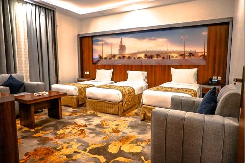 a hotel room with three beds and a large painting at فندق بلانتي 2 in Al Madinah