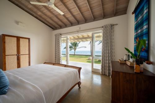 a bedroom with a bed and a view of the ocean at Nil Ralla in Talpe