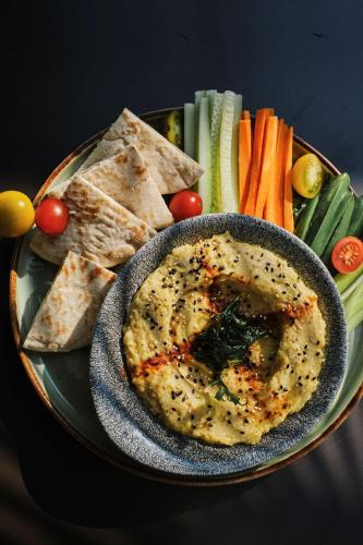 a plate of food with a bowl of dip and vegetables at Prinsotel La Pineda in Cala Ratjada