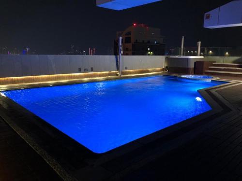 einem großen blauen Pool mit Lichtern auf einem Gebäude in der Unterkunft Sway Suites in Manama