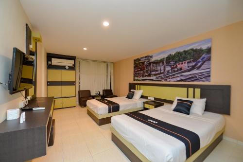 a hotel room with two beds and a desk at OYO 2487 Sampurna Jaya Hotel in Tanjung Pinang 