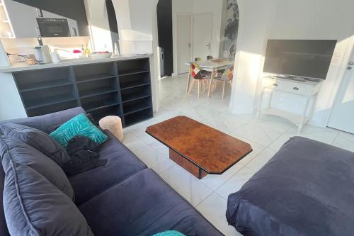 un salon avec un canapé bleu et une cuisine dans l'établissement Appartement avec vue sur la Pinède grande terrasse, à Le Touquet-Paris-Plage