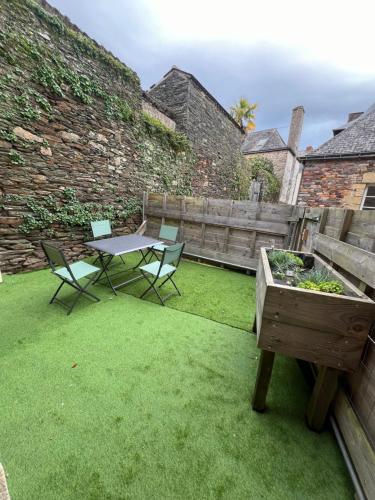a patio with a table and chairs and a table and a garden at Maison de caractère, centre ville historique in Malestroit