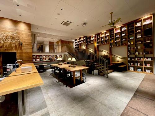 biblioteca con mesa, sillas y estanterías en Relief Kokura ANNEX Book & Stay, en Kitakyushu