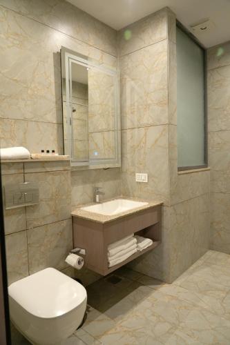 a bathroom with a white toilet and a sink at ACR Luxury Hotel in Mohali