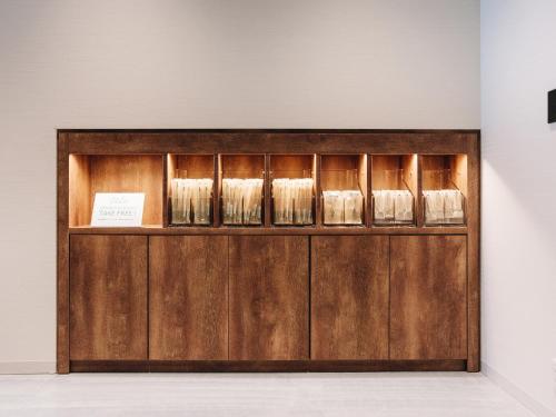 a wooden display cabinet with glasses on it at Prince Smart Inn Miyazaki in Miyazaki