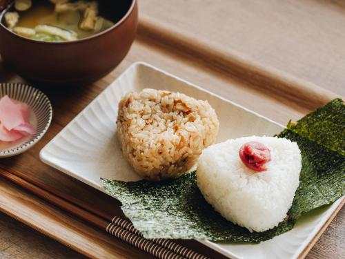 a plate of sushi with rice and a bowl of soup at Prince Smart Inn Miyazaki in Miyazaki