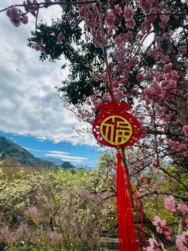 a red chinese sign hanging from a tree with flowers at Shi Bi Hotel in Gukeng
