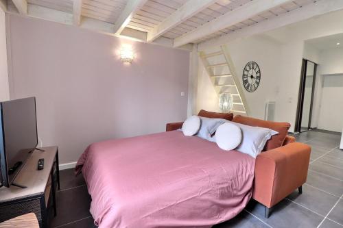 1 dormitorio con 1 cama rosa con silla y reloj en La Malterie Loft in old factory - Mon Groom, en La Chapelle-Saint-Luc