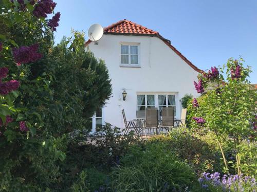 a white house with two chairs and flowers at Fischerhaus in Hooksiel