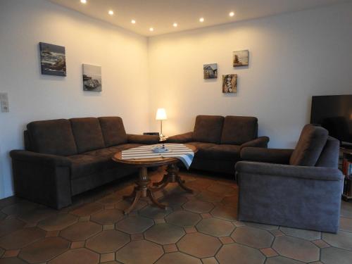 a living room with couches and a table and a tv at Haus Wattkieker in Hooksiel