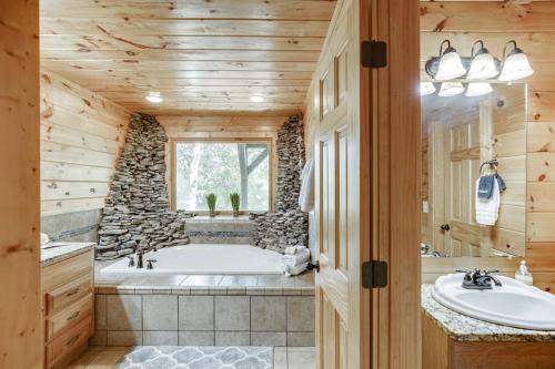 La salle de bains est pourvue d'une baignoire et d'un mur en pierre. dans l'établissement Deluxe Cabin For Groups Near Helen w Hot Tub, à Cornelia