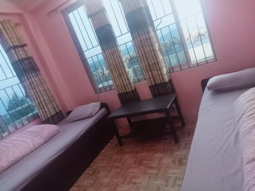 a room with two beds and a table and windows at Namobuddha Hotel n Lodge in Dhulikhel