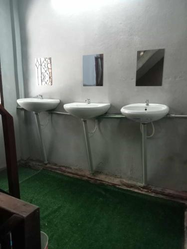 three sinks in a bathroom with green flooring at Bang lumphu house&bistro in Bangkok
